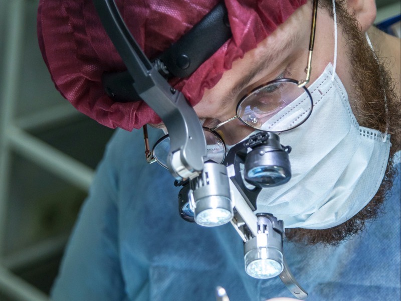 A surgeon wearing magnifying loupes with a headlight