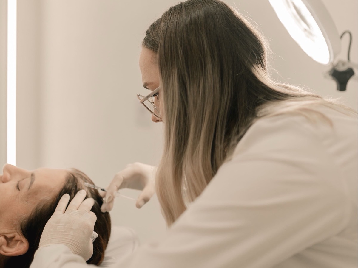 A clinician placing a fine needle in a patient's scalp